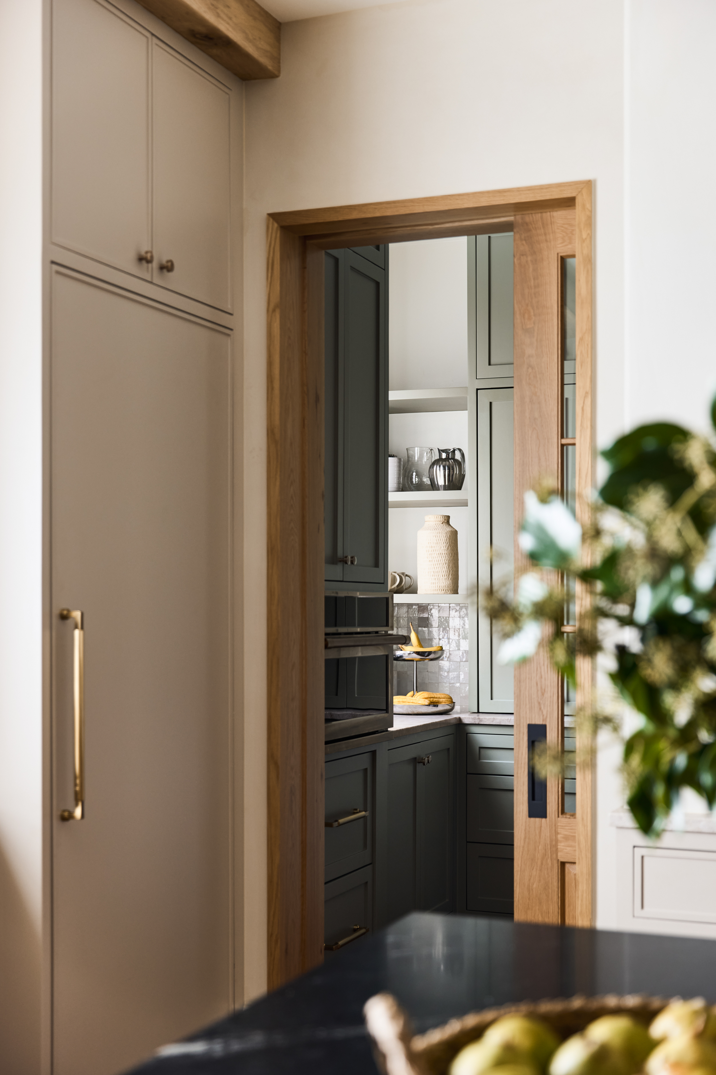 Kitchen cabinetry detail framed through an oak pocket door