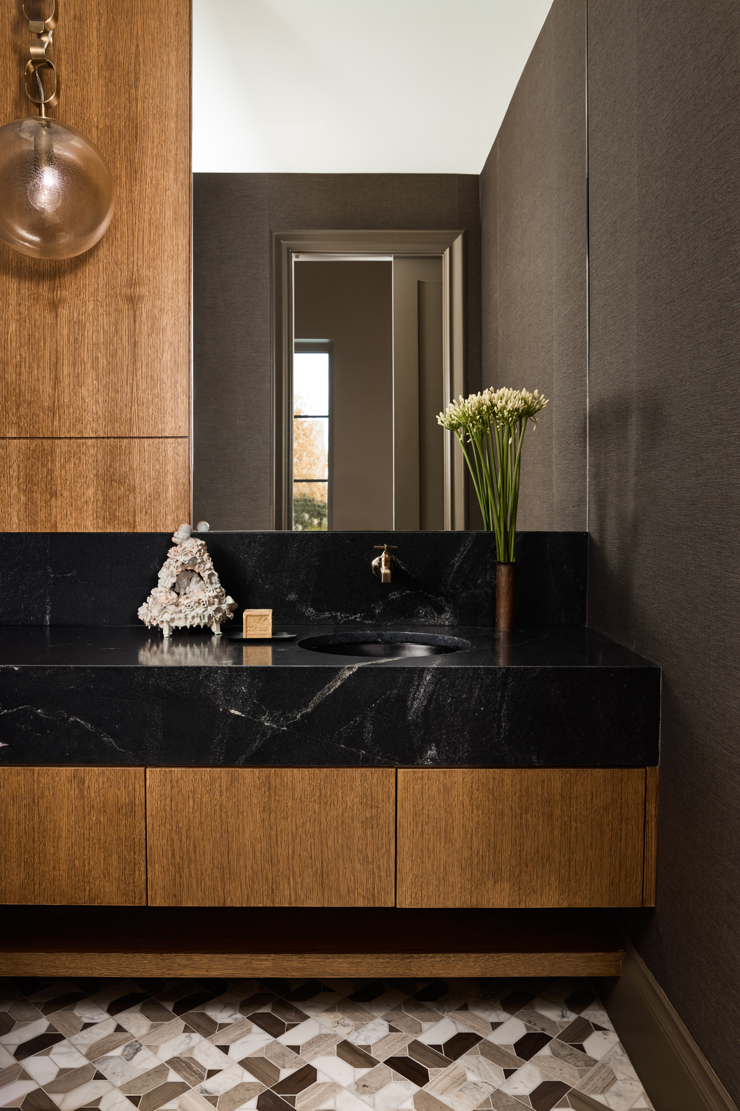 Powder room with black stone vanity and oak cabinetry